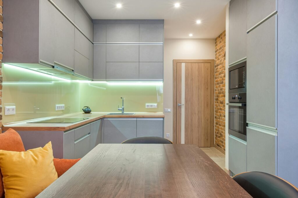 Contemporary kitchen design with modern lighting and brick accent wall.