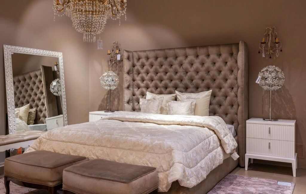 Luxurious bedroom featuring a tufted headboard, chandelier, and elegant decor.