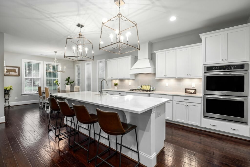 Sleek modern kitchen featuring white cabinetry, spacious island, and stylish lighting for a contemporary home design.
