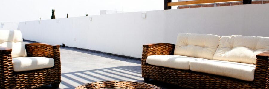 Sunny rooftop terrace with stylish wicker furniture and neutral cushions.