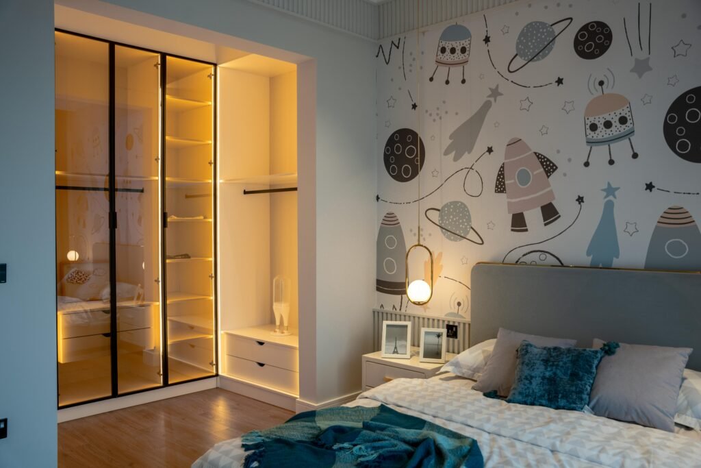 A cozy and stylish kid's bedroom featuring space-themed wallpaper and modern furnishings.