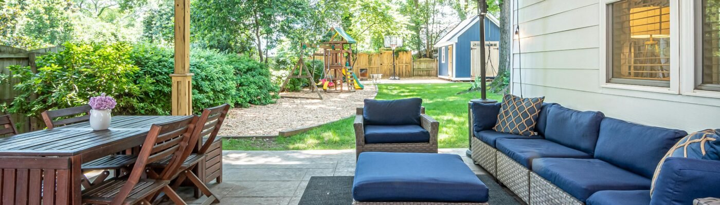 A charming backyard patio featuring cozy seating and a wooden dining set, perfect for outdoor relaxation.