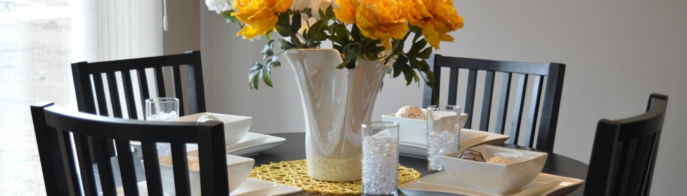 A stylish dining area featuring a round table with vibrant floral centerpiece and modern tableware.