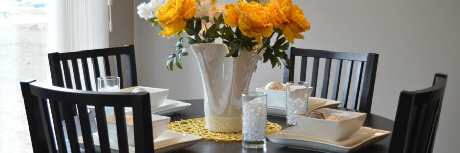 A stylish dining area featuring a round table with vibrant floral centerpiece and modern tableware.