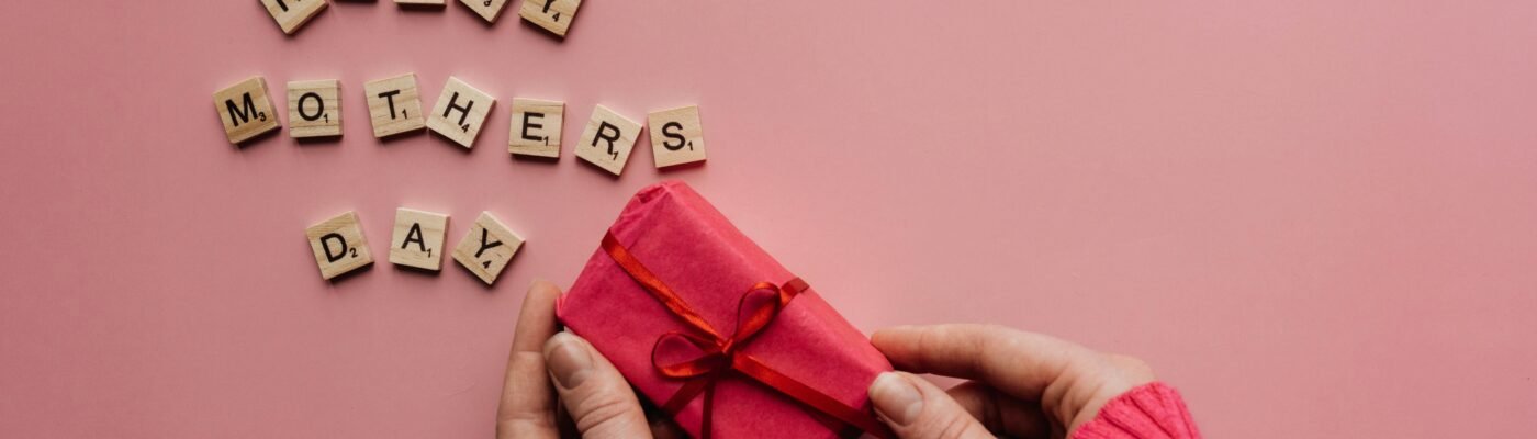 A heartfelt Mother's Day greeting with a gift on a pink background.